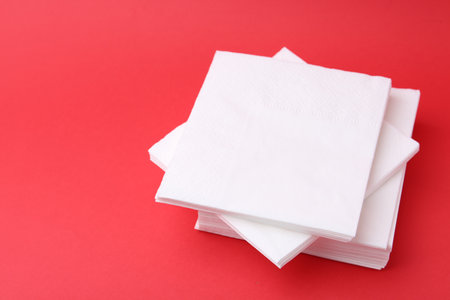 Stack of white handkerchiefs on red background, closeup. Space for textの写真素材