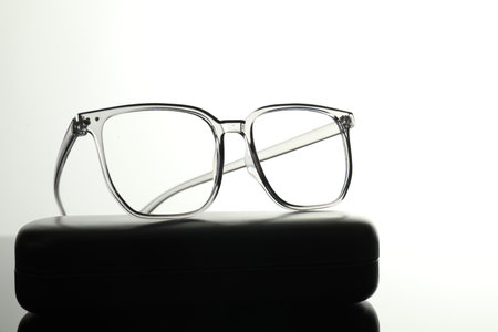 Stylish glasses and case on white mirror surface, closeupの写真素材