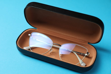 Case with stylish glasses on light blue background, closeupの写真素材