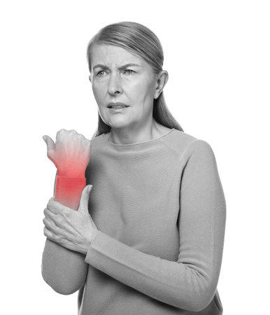 Arthritis. Senior woman suffering from wrist pain on white background. Black and white toning with...