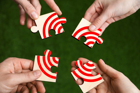 Targeting. People putting puzzle pieces together to make image of bullseye over green grass, top...