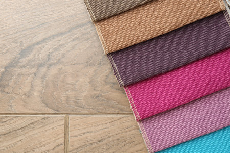 Samples of different fabrics on wooden table, top view. Space for text