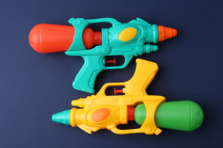 Bright plastic water guns on dark blue background, top viewの写真素材