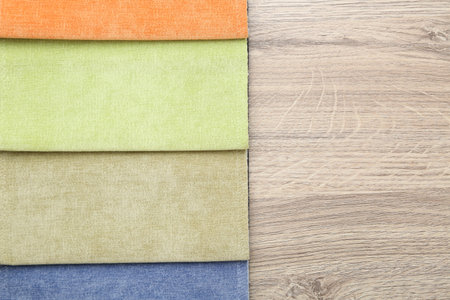 Samples of different fabrics on wooden table, top view. Space for text
