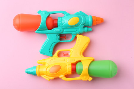 Bright plastic water guns on light pink background, top viewの写真素材