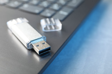 Flash drive and laptop on table, closeup