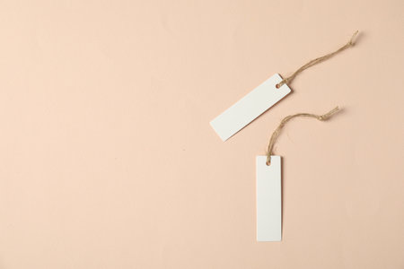 Blank tags with strings on beige background, flat lay. Space for textの写真素材