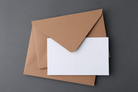Blank greeting card and envelopes on grey background, top view