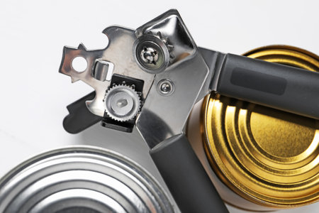 Can opener and tins on white table, flat layの写真素材