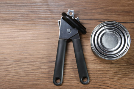 Can opener and tin on wooden table, top view. Space for textの写真素材