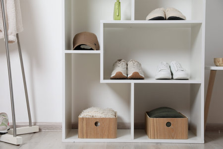 Shelving unit with different footwear, clothes and accessories indoors. Shoe storage