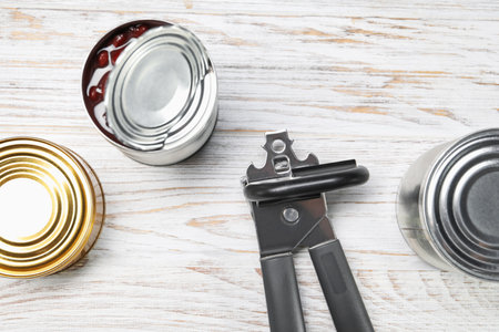 Can opener and tins on white wooden table, flat layの写真素材