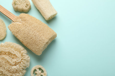Natural loofah sponges on light blue background, flat lay. Space for textの写真素材