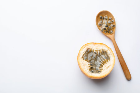 Ripe passion fruit, seeds and spoon on white background, flat lay. Space for text