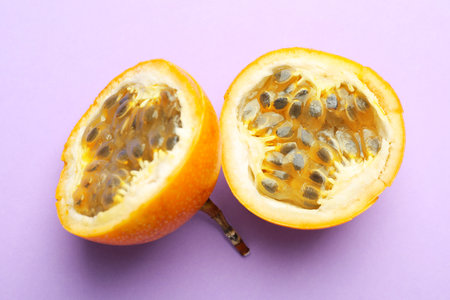 Pieces of ripe yellow passion fruit on lilac background, top viewの写真素材