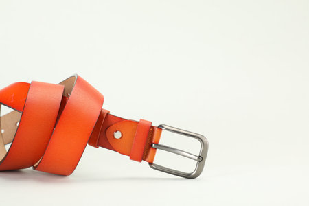 One orange leather belt on white background, closeup. Space for textの写真素材