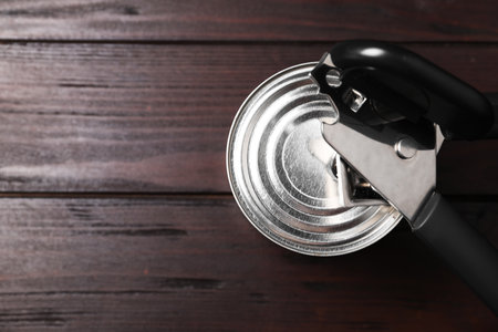 Can opener and tin on wooden table, top view. Space for textの写真素材