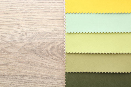 Samples of different fabrics on wooden table, top view. Space for text