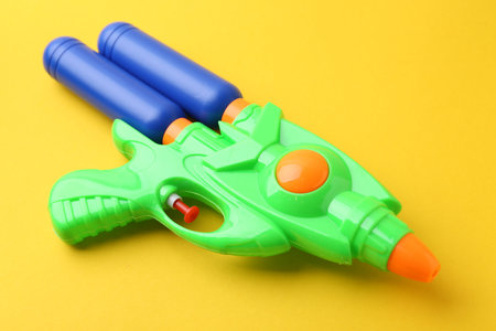 Bright plastic water gun on yellow background, closeupの写真素材