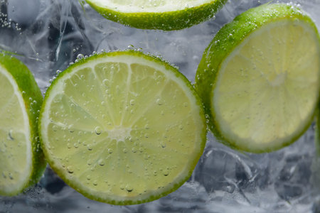 Refreshing soda water with slices of lime and ice in glass on dark background, closeupの写真素材