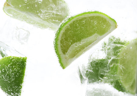 Refreshing soda water with slices of lime and ice in glass on white background, closeupの写真素材
