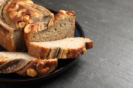 Cut banana bread with nuts on black table, closeup. Space for textの写真素材