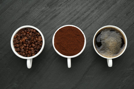 Aromatic ground coffee, beans and hot drink on black table, flat layの写真素材