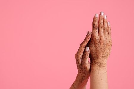 Woman applying body scrub onto her hands on pink background, closeup. Space for textの写真素材