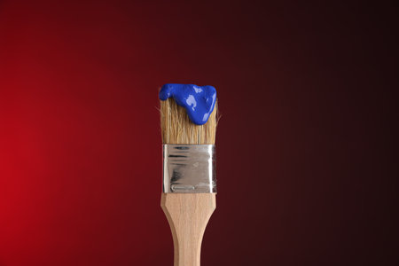 Brush with blue paint on red background, closeupの写真素材