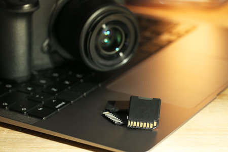 SD memory cards, laptop and photo camera on wooden table, closeupの写真素材