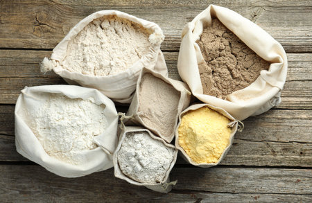 Different types of flour in bags on wooden table, flat layの写真素材