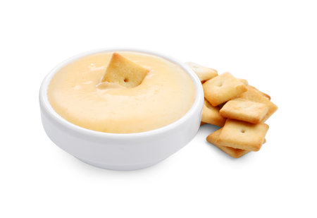 Tasty cheese dipping sauce in bowl and crackers isolated on whiteの写真素材