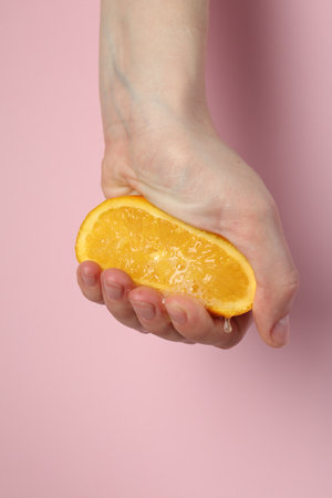 Woman squeezing orange on pink background, closeupの写真素材