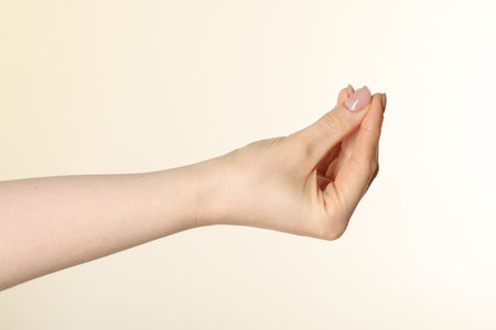 Woman holding something in hand on beige background, closeupの写真素材