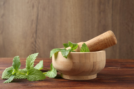 Fresh lemon balm leaves, pestle and mortar on wooden table, closeupの写真素材