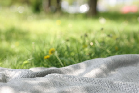 Light grey blanket for picnic on green grass outdoors, closeupの写真素材