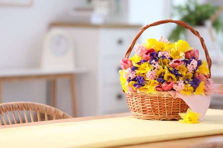 Wicker basket with beautiful flowers on table indoors. Space for textの写真素材