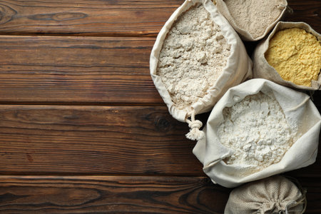Different types of flour in bags on wooden table, flat lay. Space for textの写真素材