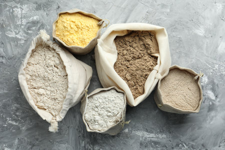 Different types of flour in bags on grey textured table, flat layの写真素材