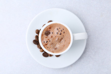 Aromatic coffee in cup, beans and saucer on light table, top viewの写真素材