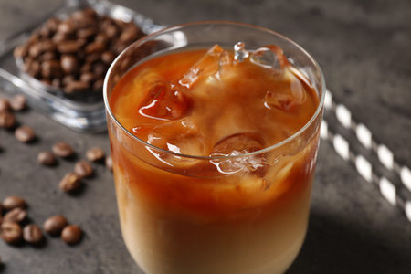 Tasty iced coffee and beans on grey table, closeup
