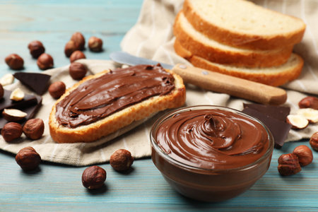 Toast with tasty chocolate hazelnut spread and nuts on blue wooden table, closeupの写真素材