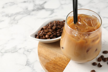 Tasty iced coffee and beans on white marble table, closeup. Space for textの写真素材