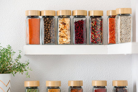 Different aromatic spices in jars on white shelf indoorsの写真素材