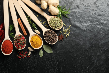 Many different spices in spoons on black table, flat lay. Space for textの写真素材