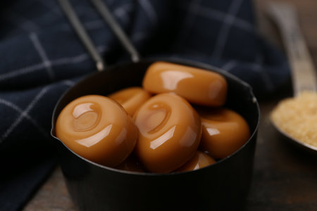Tasty sweet caramel candies and sugar on wooden table, closeupの写真素材