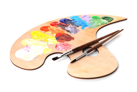 Wooden palette with paints and brushes isolated on whiteの写真素材
