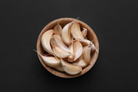 Aromatic garlic in bowl on dark table, top viewの写真素材