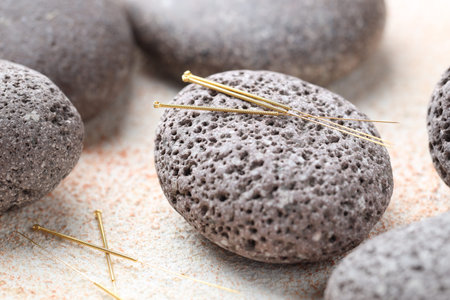 Acupuncture needles and spa stones on light textured table, closeupの写真素材