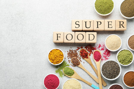 Different superfood powders and words made of cubes on light grey table, flat lay. Space for textの写真素材